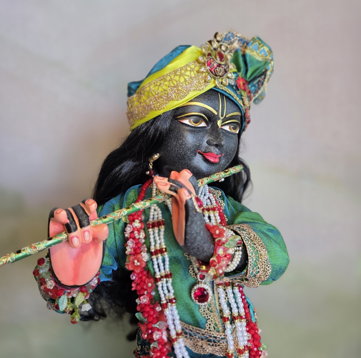 Luxurious black Marble deity of Gopinath Krishna standing with flute to His nectarian lips. Gopinath a hand-carved black marble Krishna deity, 18 inches tall, with 7 outfits & flower-jewel shringar included. One of a kind — free shipping. Dressed in citrine yellow and kingfisher blue green with garlands of everfresh flowers and pearl jewelery