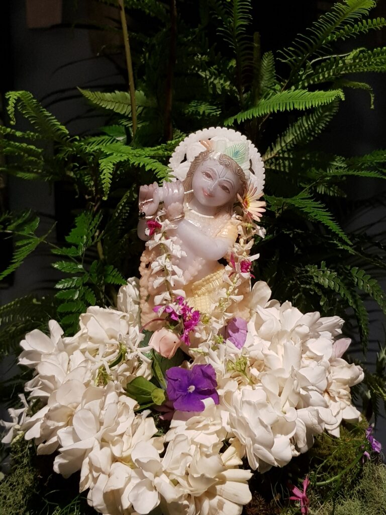 sweet small form of krishna in marble with flowers