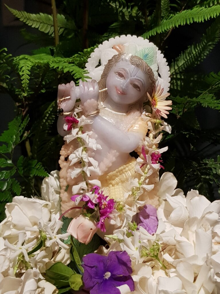 covered in flowers marble deity of krishna