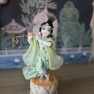 deity of Krishna named Balagopal carved in white marble with a mild blue colorwash. standing on a lotus carved base with miny shringar
